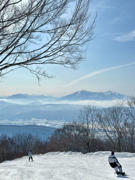 snowboarder riding down skyline sunny