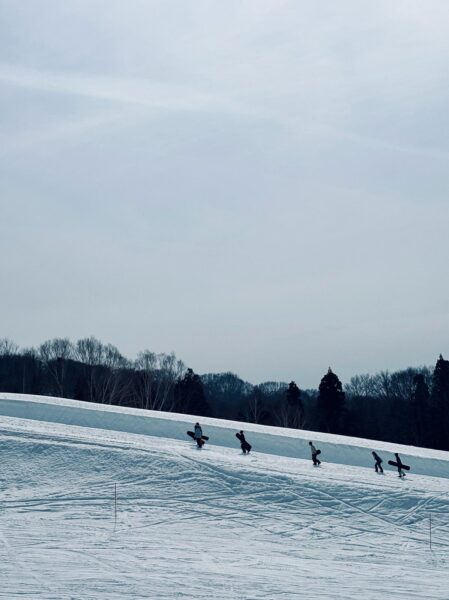 group of snowboarders walking the halfpipe